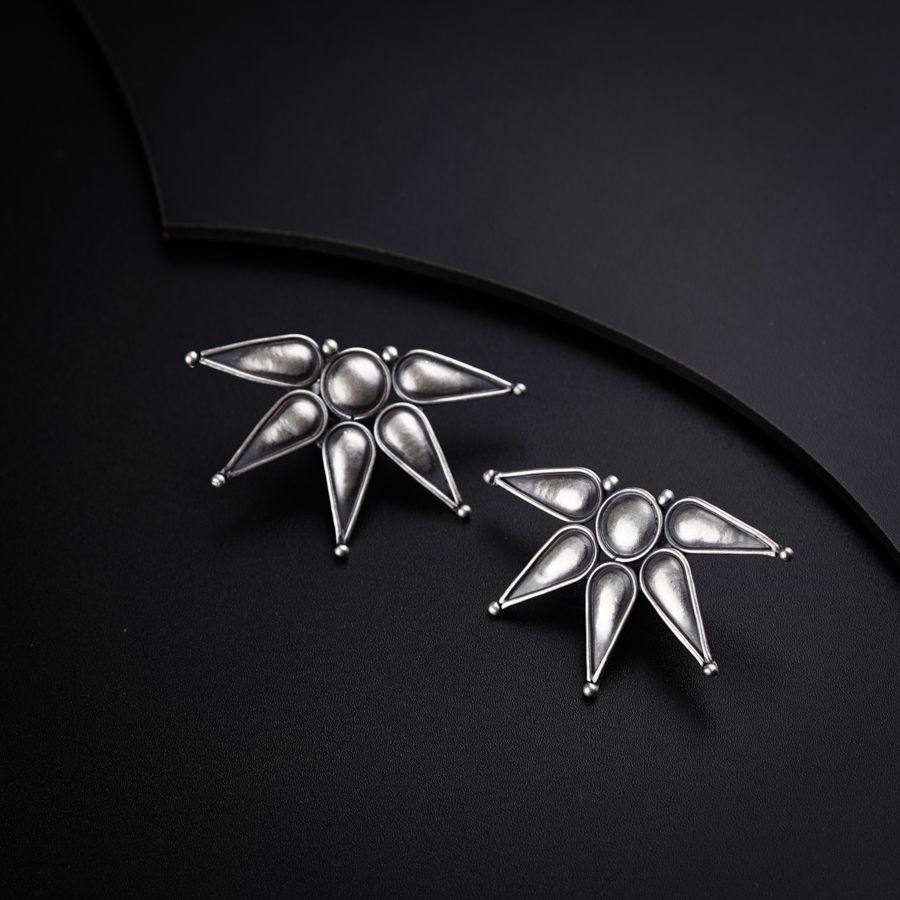a pair of silver earrings sitting on top of a black surface