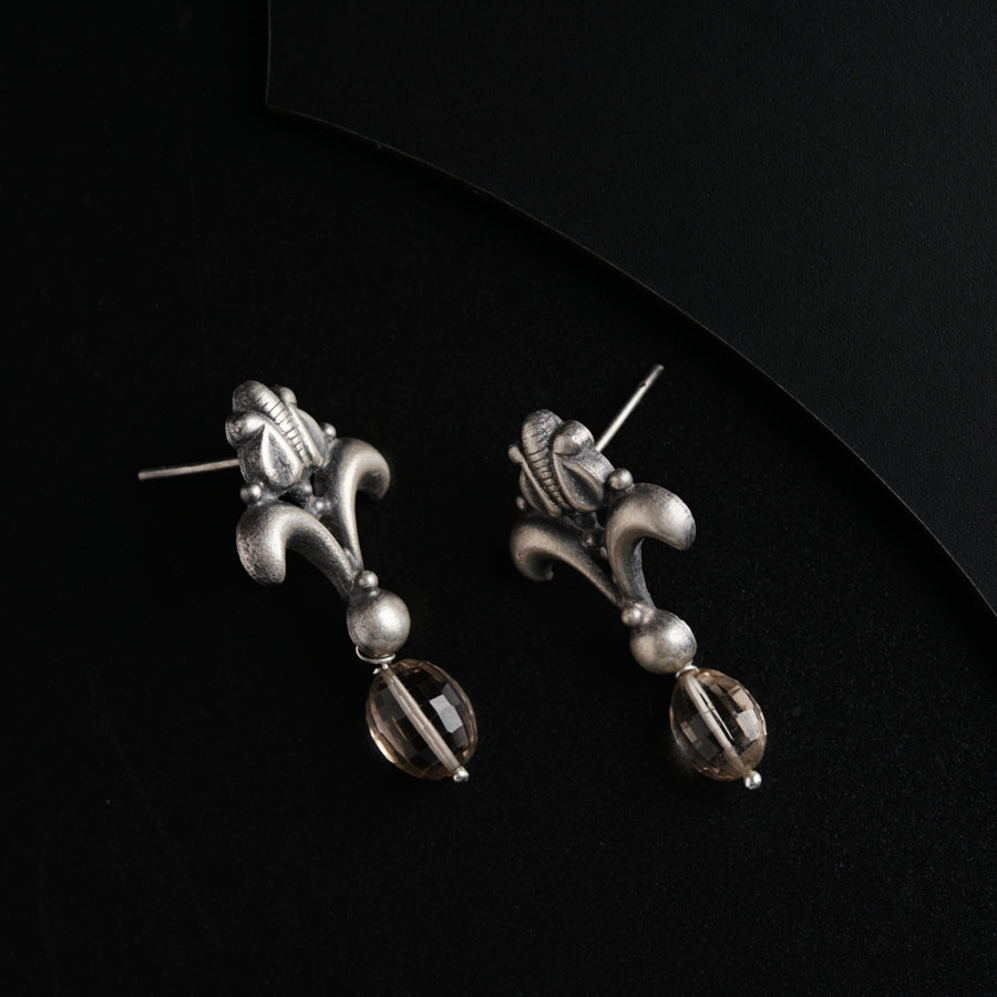 a pair of silver earrings sitting on top of a black surface