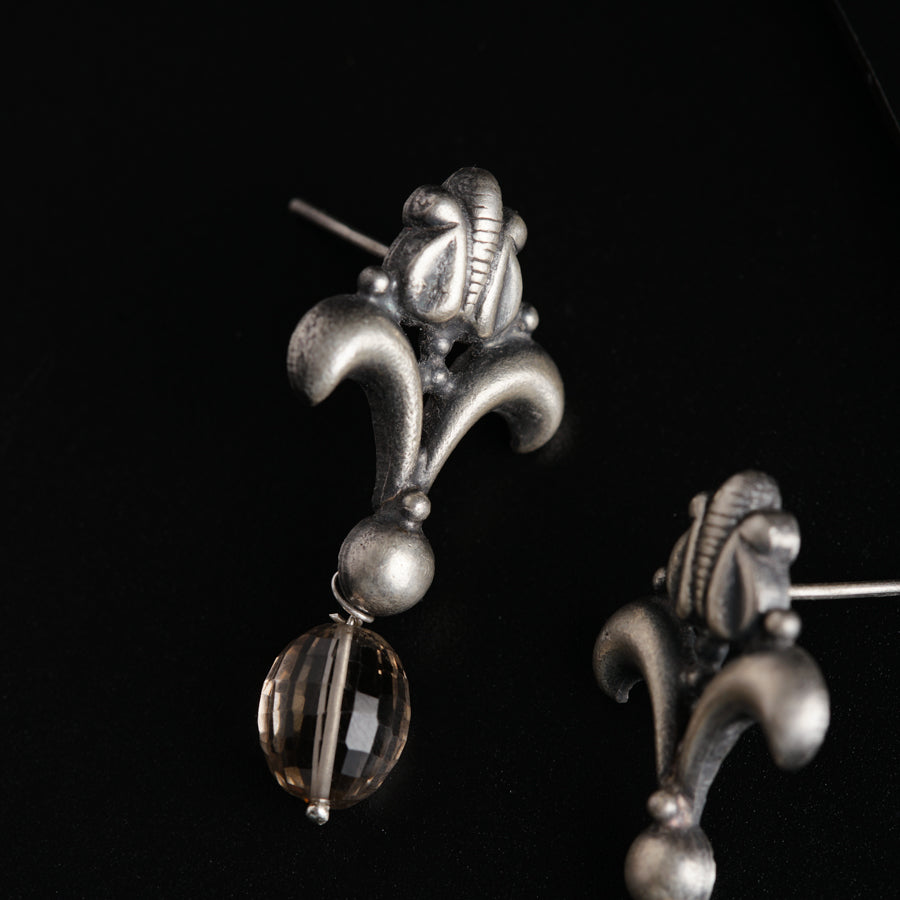 a pair of earrings is shown on a black surface