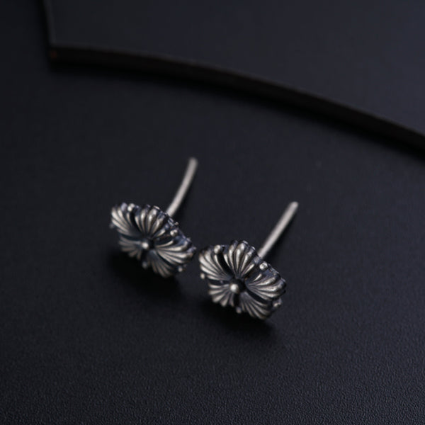 a pair of silver earrings sitting on top of a black surface