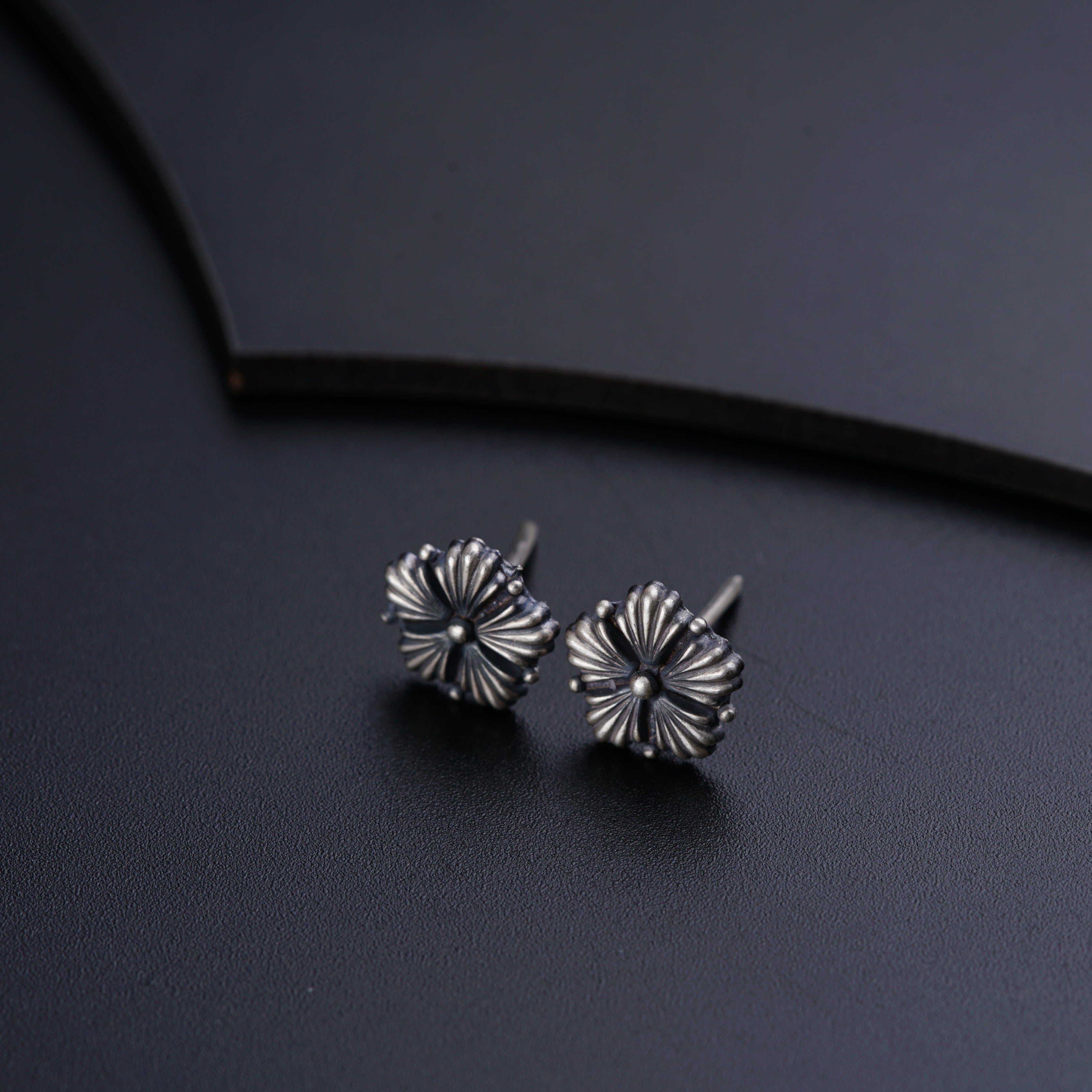 a pair of silver earrings sitting on top of a table