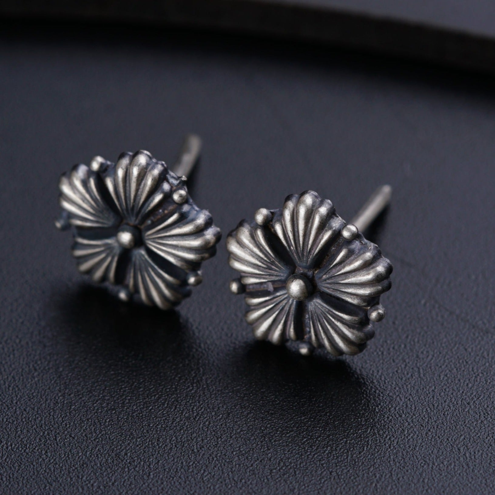 a pair of silver earrings sitting on top of a table