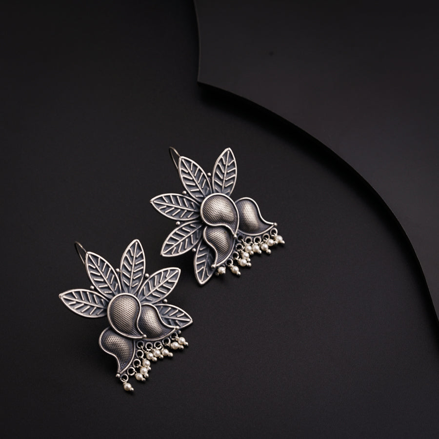 a pair of earrings with leaves and pearls