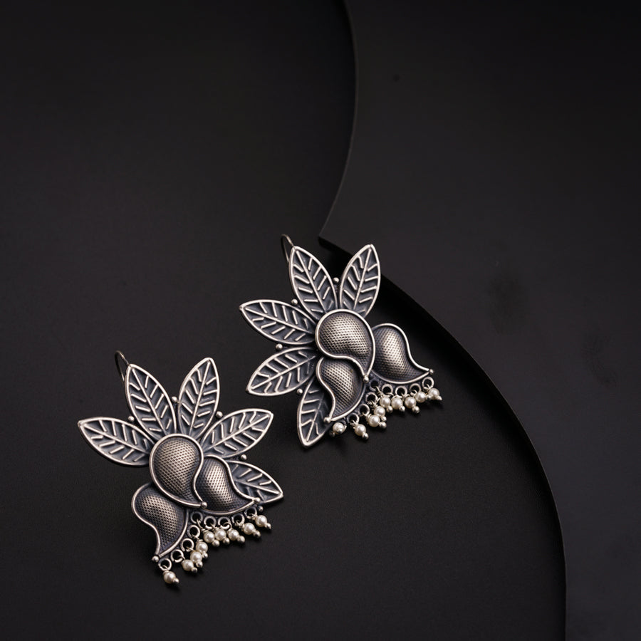 a pair of earrings with leaves and pearls