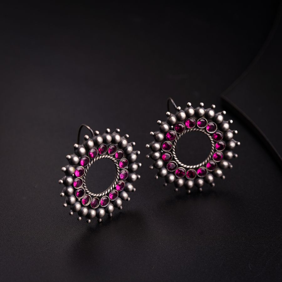 a pair of pink and silver earrings on a black surface