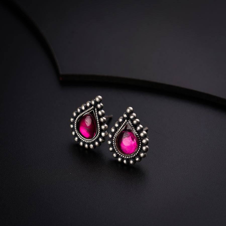 a pair of pink stone earrings on a black surface