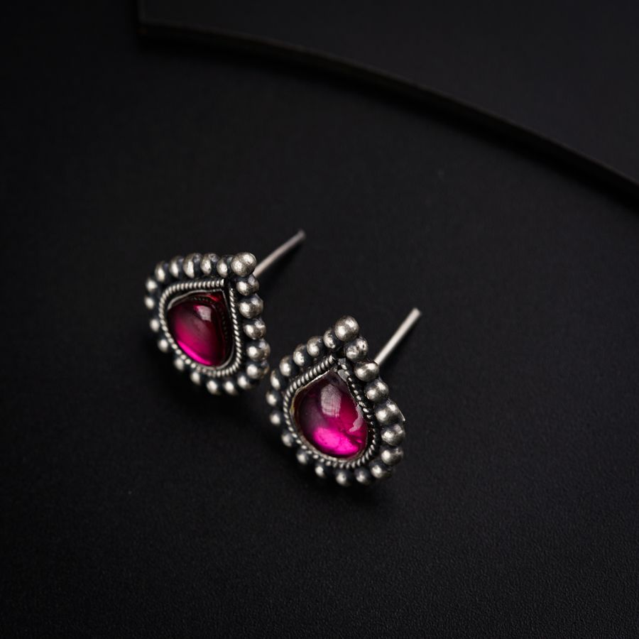 a pair of pink stone earrings on a black surface