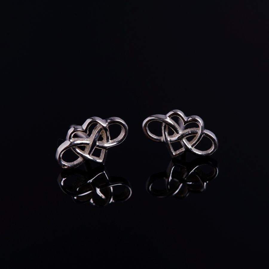 a pair of silver earrings on a black background
