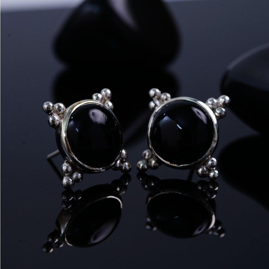 a pair of black stone earrings sitting on top of a table