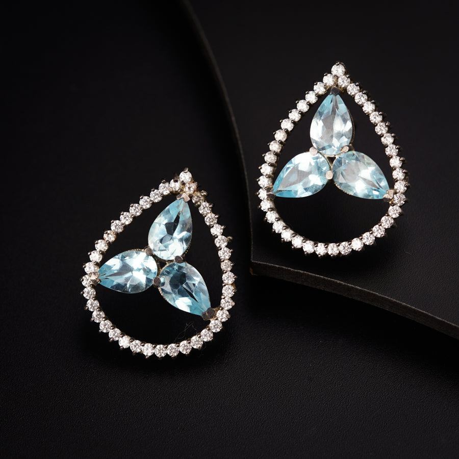 a pair of blue and white earrings on a black surface
