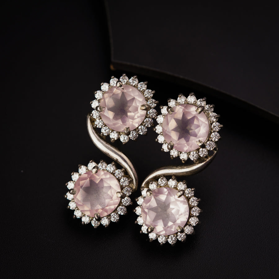 a pair of pink and white stone brooches on a black surface