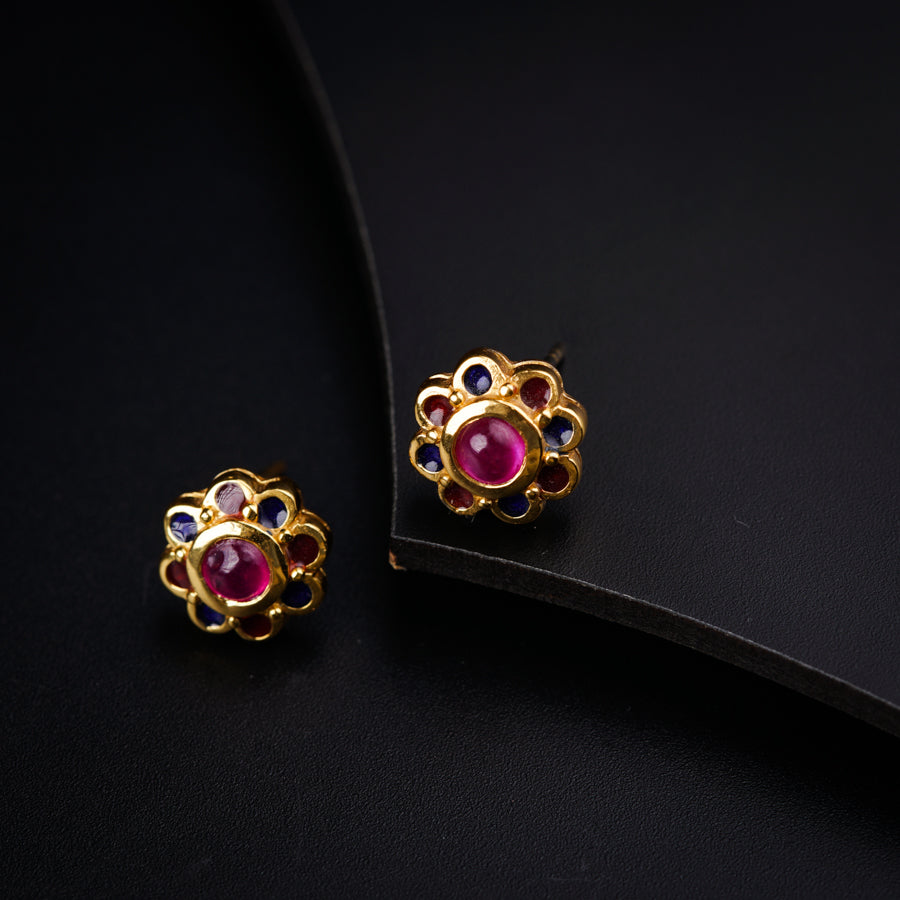 a pair of pink and blue earrings sitting on top of a black surface