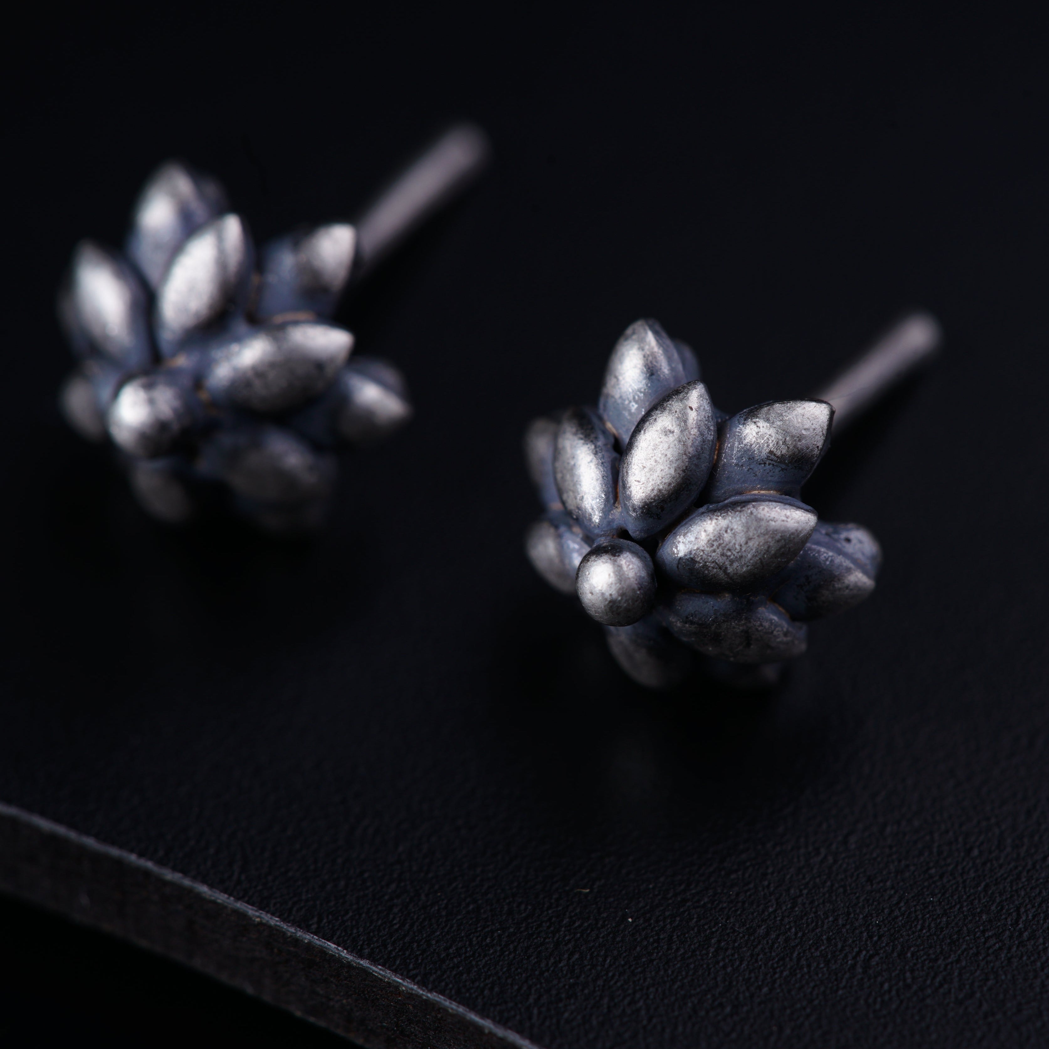 a pair of silver earrings sitting on top of a black surface