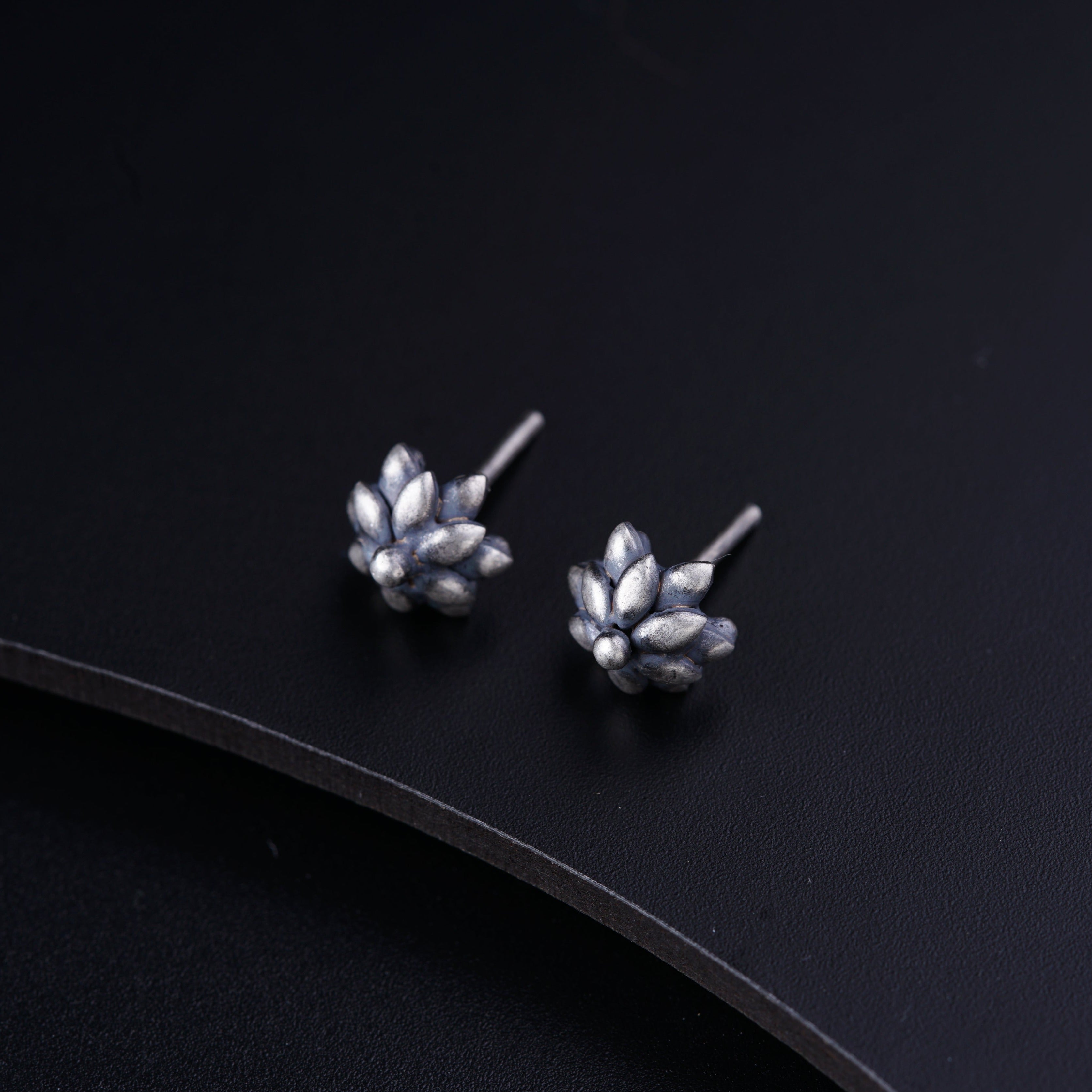 a pair of silver earrings sitting on top of a black surface