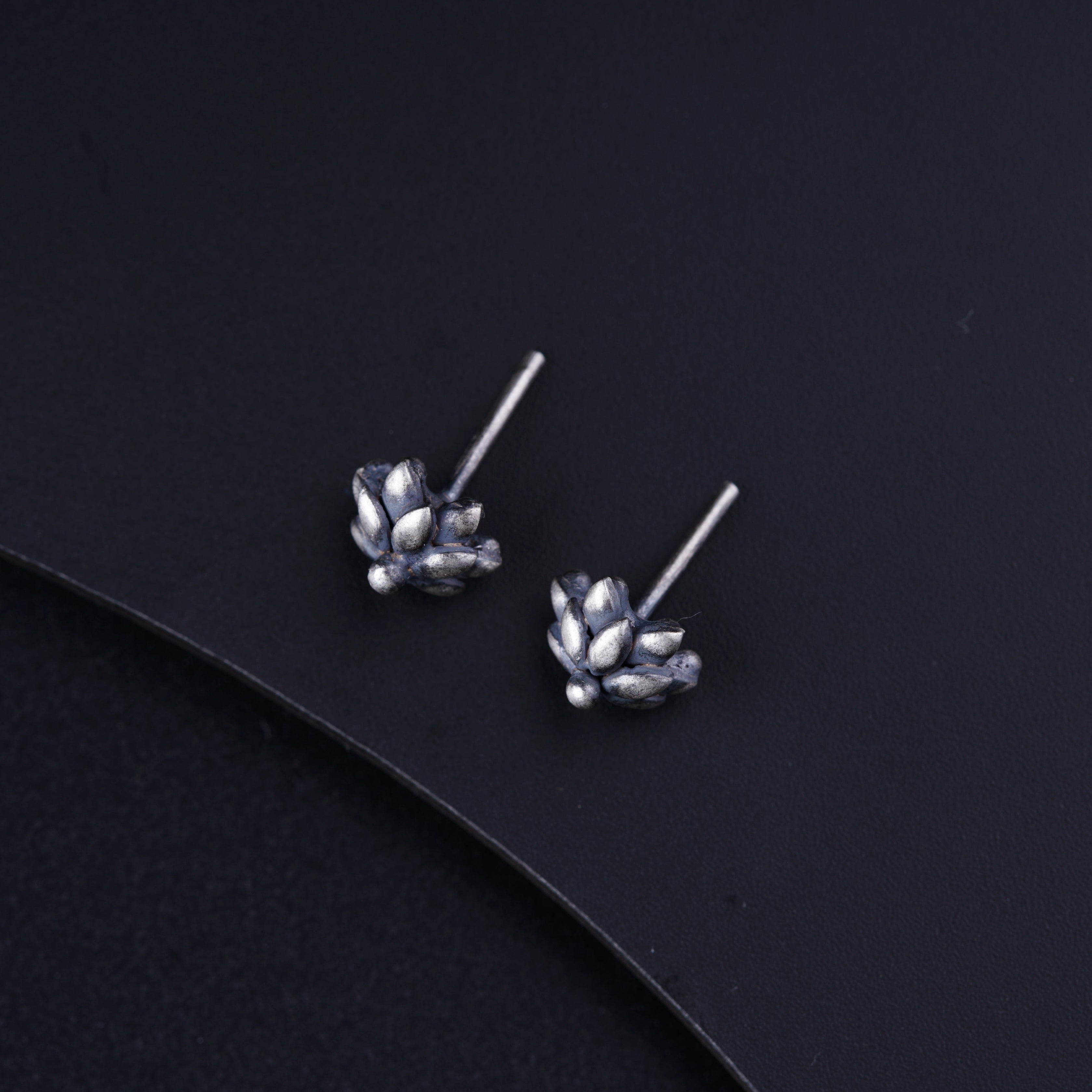 a pair of silver flower earrings on a black surface