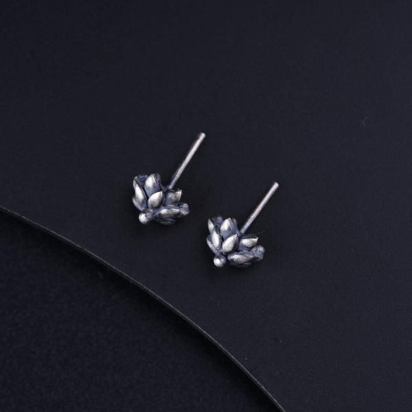 a pair of silver flower earrings on a black surface
