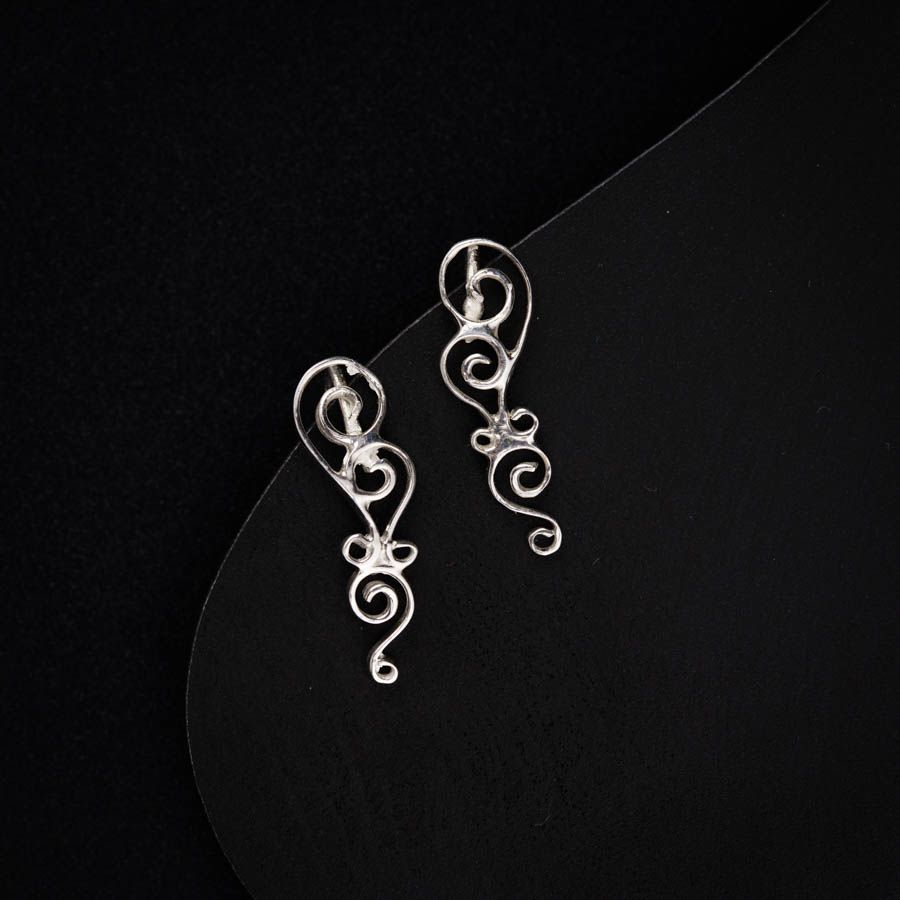 a pair of silver earrings on a black background