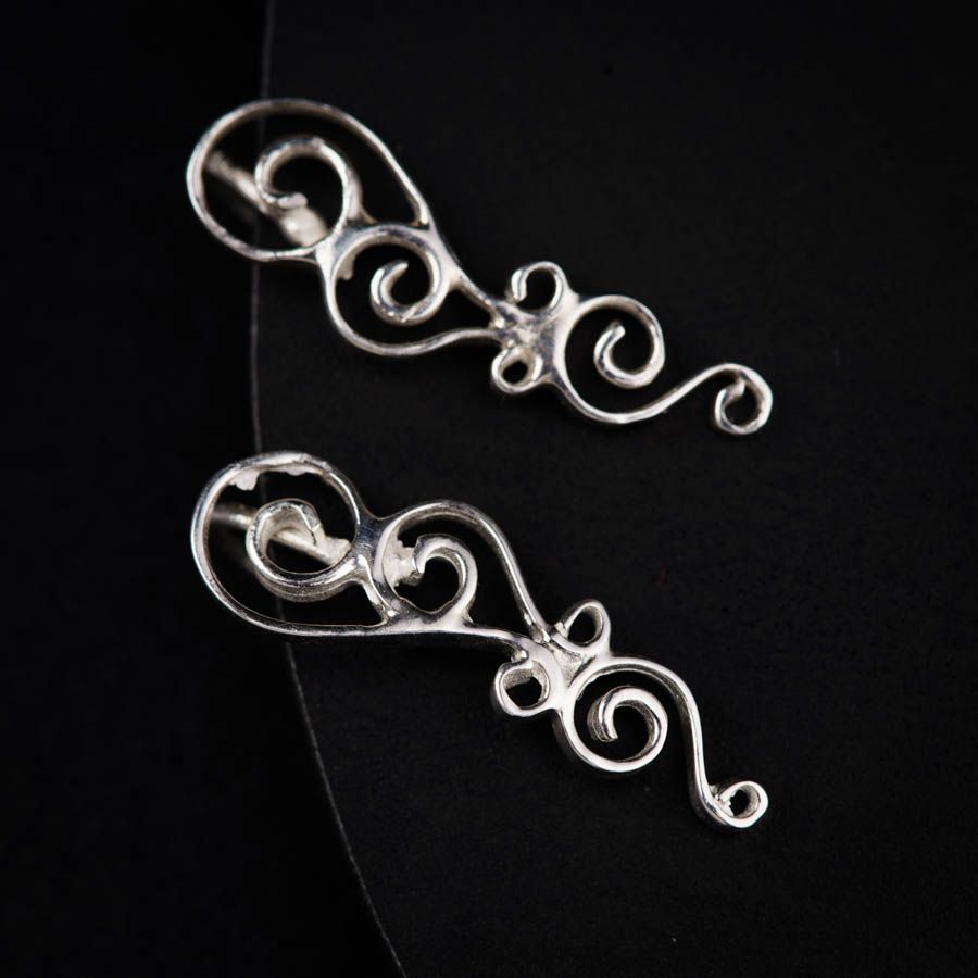 a pair of silver earrings on a black surface