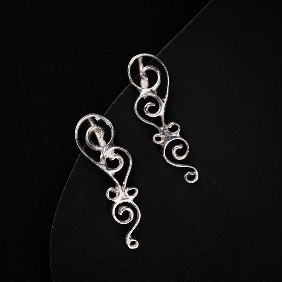a pair of silver earrings sitting on top of a table