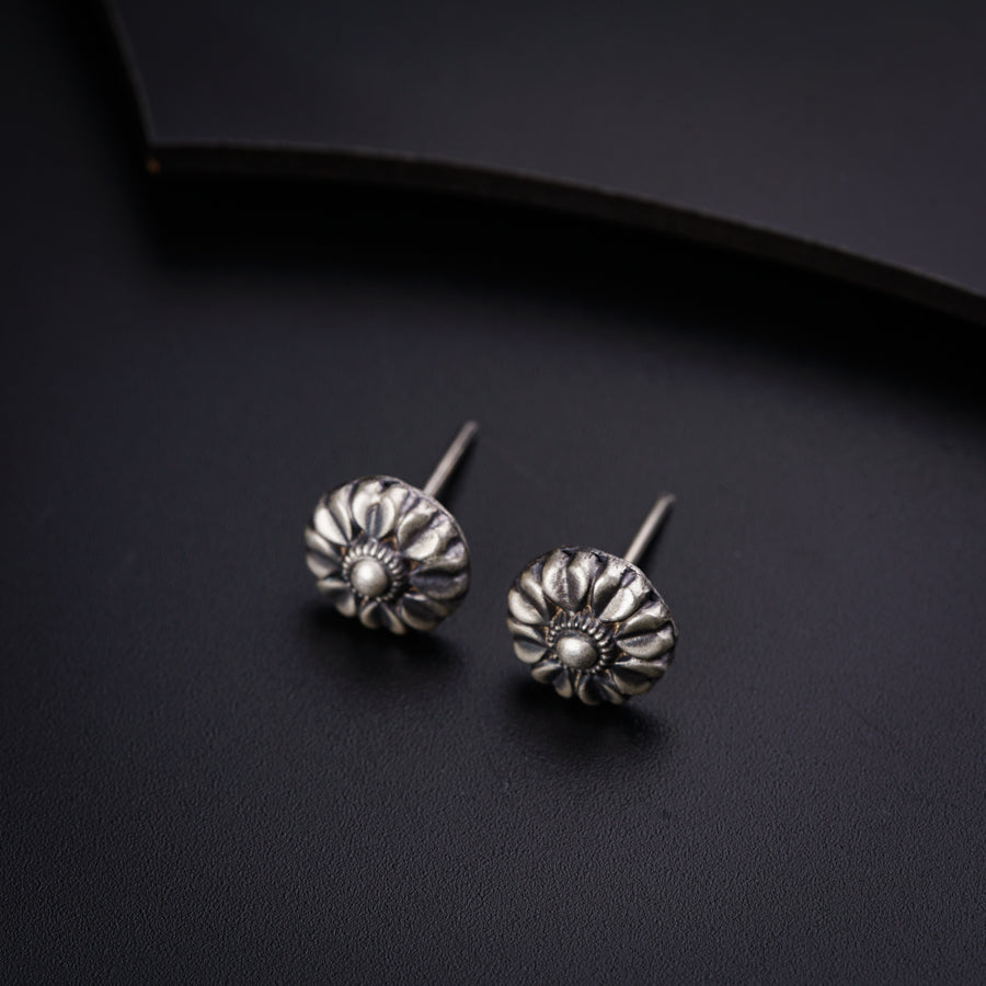 a pair of silver earrings sitting on top of a black surface