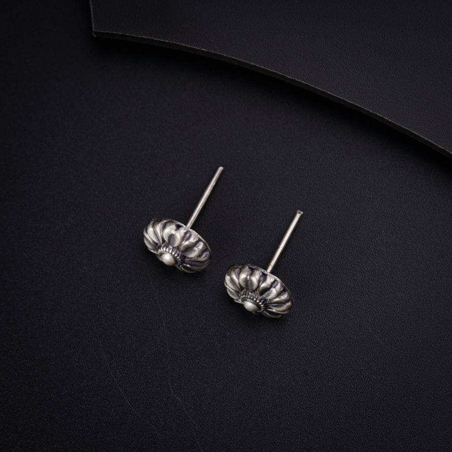 a pair of silver earrings sitting on top of a black surface