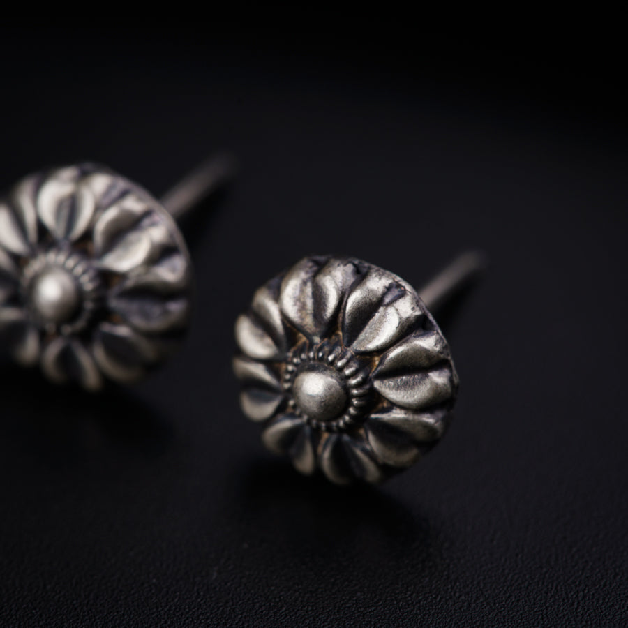 a pair of silver earrings sitting on top of a black surface