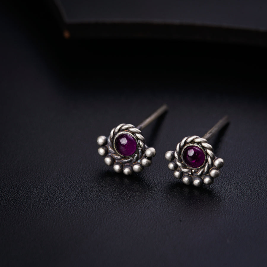 a pair of silver earrings with a purple stone