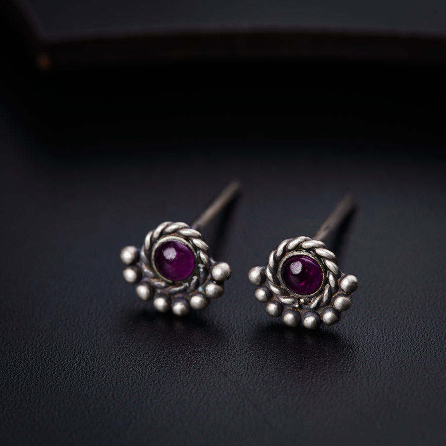 a pair of silver earrings with a purple stone
