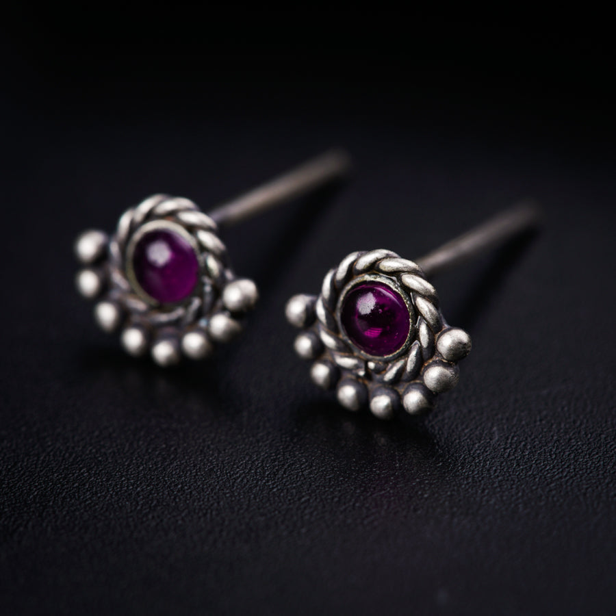 a pair of silver earrings with a purple stone