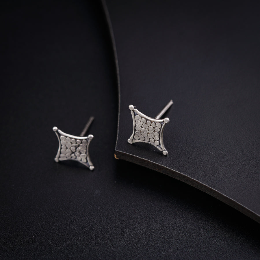 a pair of earrings sitting on top of a black surface