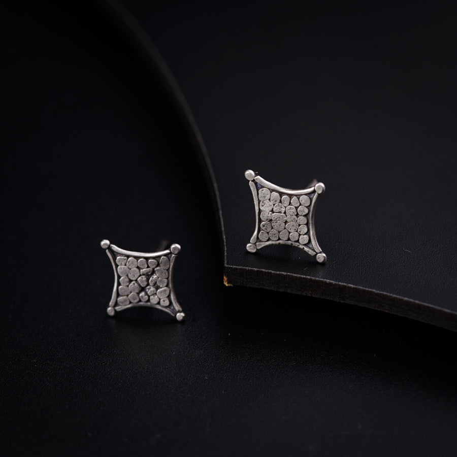a pair of earrings sitting on top of a black surface