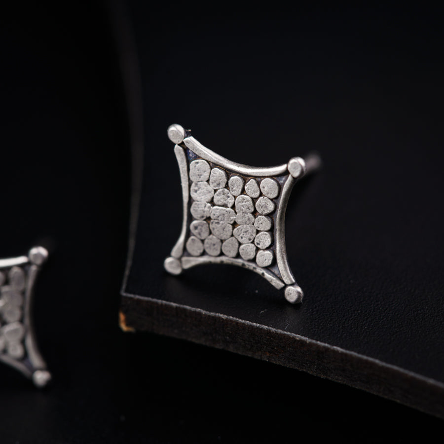 a pair of diamond earrings sitting on top of a black surface