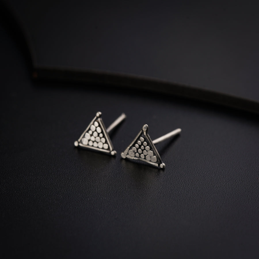 a pair of triangle shaped earrings on a black surface