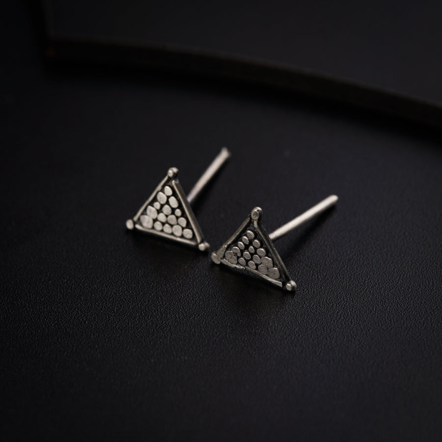 a pair of triangle shaped earrings on a black surface