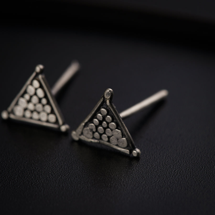 a pair of triangle shaped earrings on a black surface