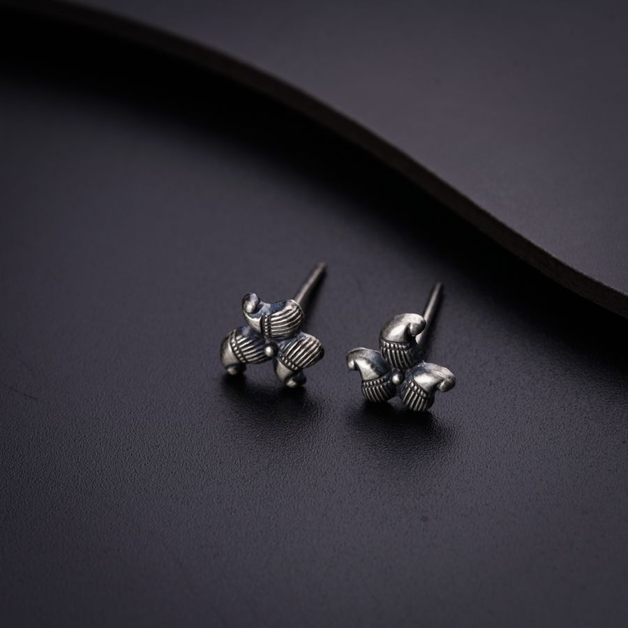 a pair of silver earrings on a black surface