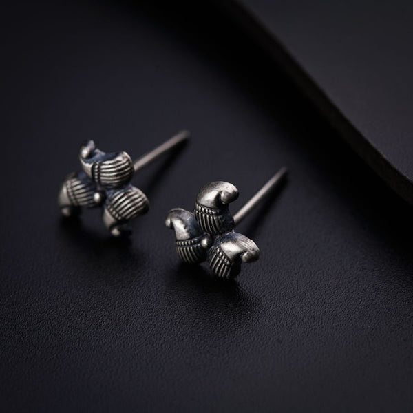 a pair of silver earrings sitting on top of a black surface