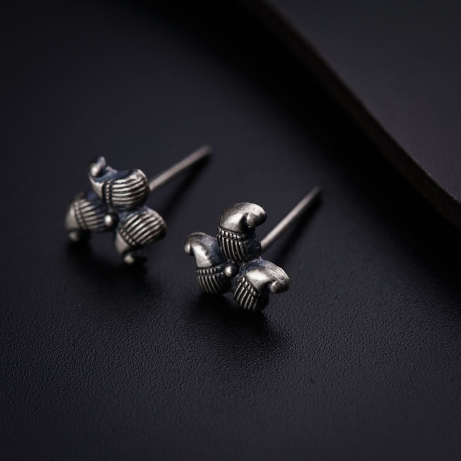 a pair of silver earrings sitting on top of a black surface