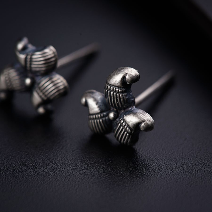 a pair of silver earrings sitting on top of a black surface