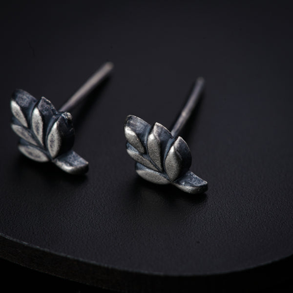a pair of silver earrings on a black surface