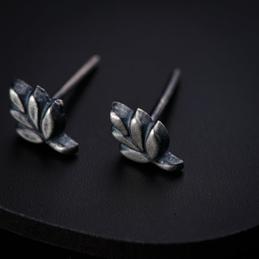 a pair of silver earrings on a black surface