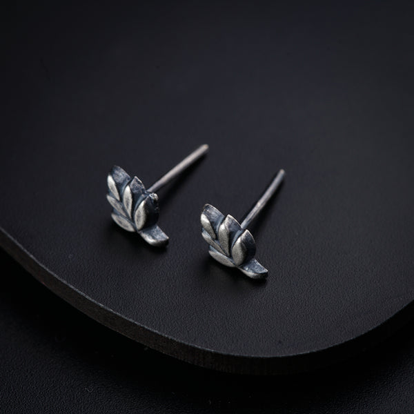 a pair of silver earrings sitting on top of a black surface