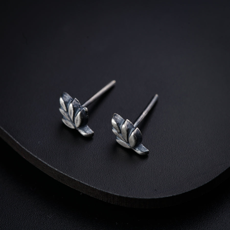 a pair of silver earrings sitting on top of a black surface