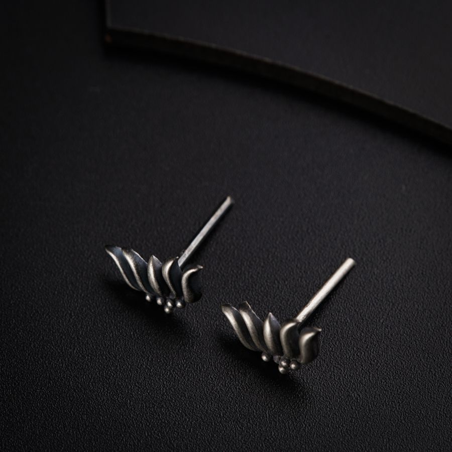 a pair of silver earrings sitting on top of a black surface
