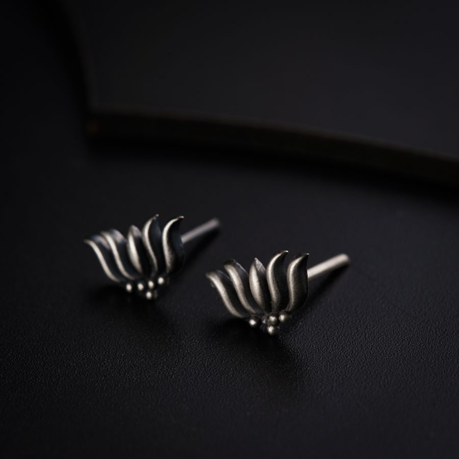 a pair of silver earrings sitting on top of a black surface
