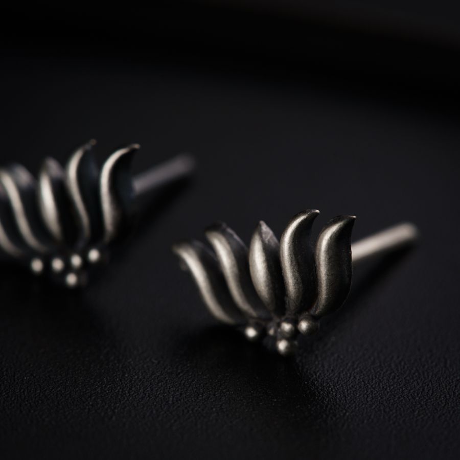 a pair of silver earrings sitting on top of a black surface