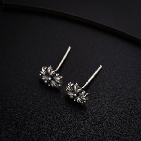 a pair of silver earrings on a black surface