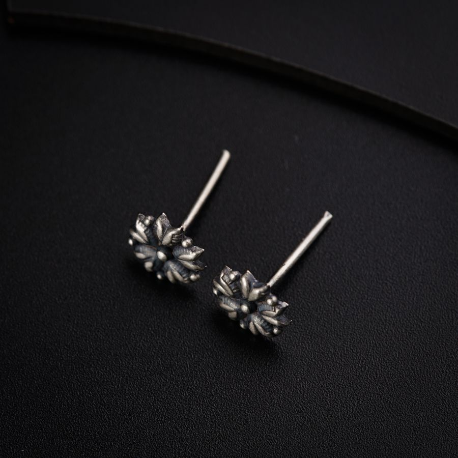 a pair of silver earrings on a black surface
