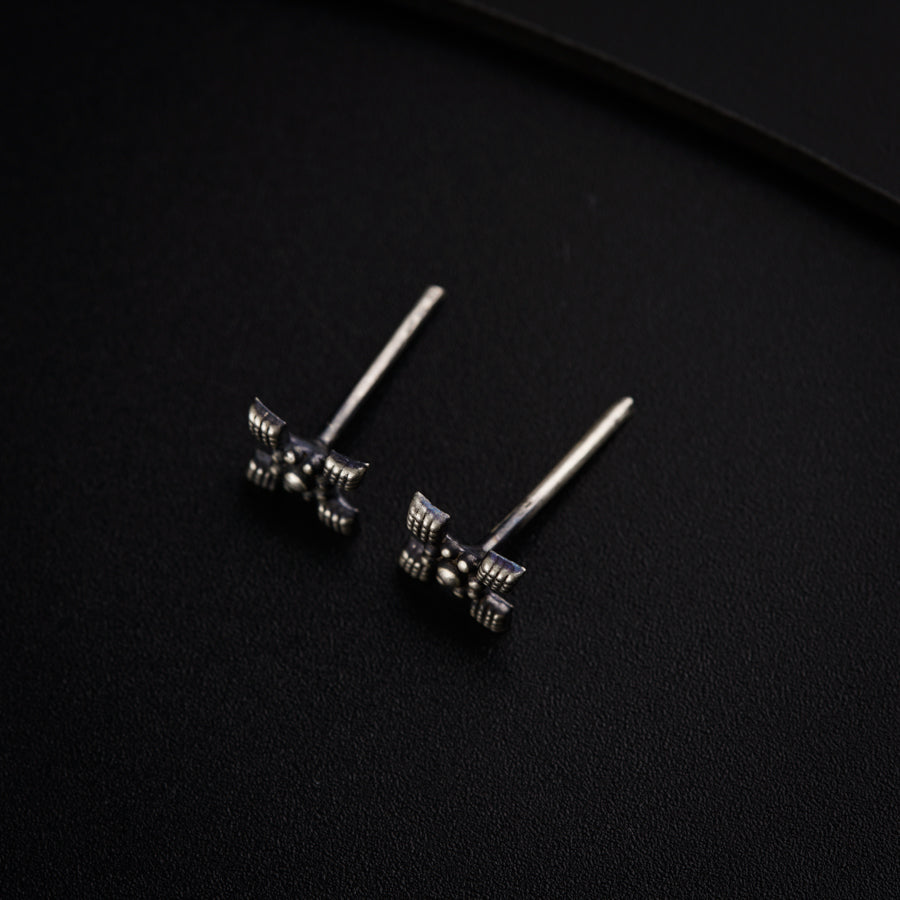 a pair of silver earrings on a black surface