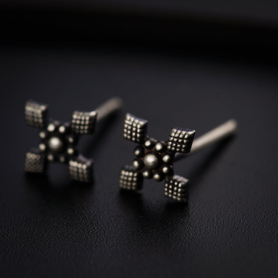 a pair of silver earrings on a black surface